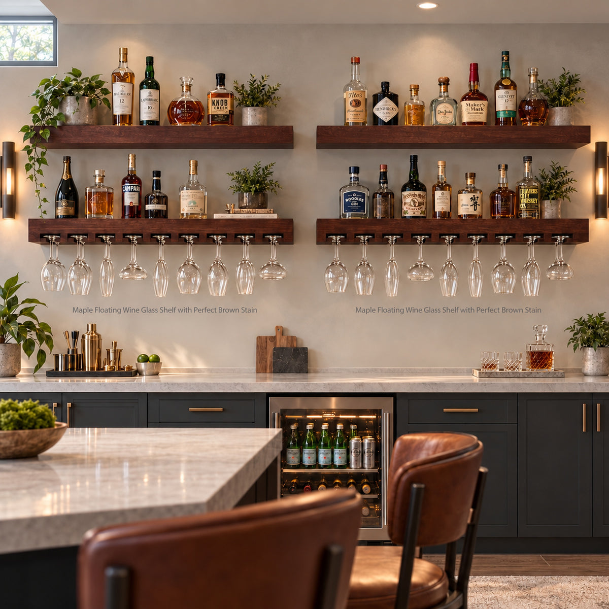 A modern bar setup with two floating wooden wine shelves mounted on a light beige wall. The shelves are styled with an assortment of liquor bottles, small potted green plants, and each have eighteen hanging wine glasses and other stemware.